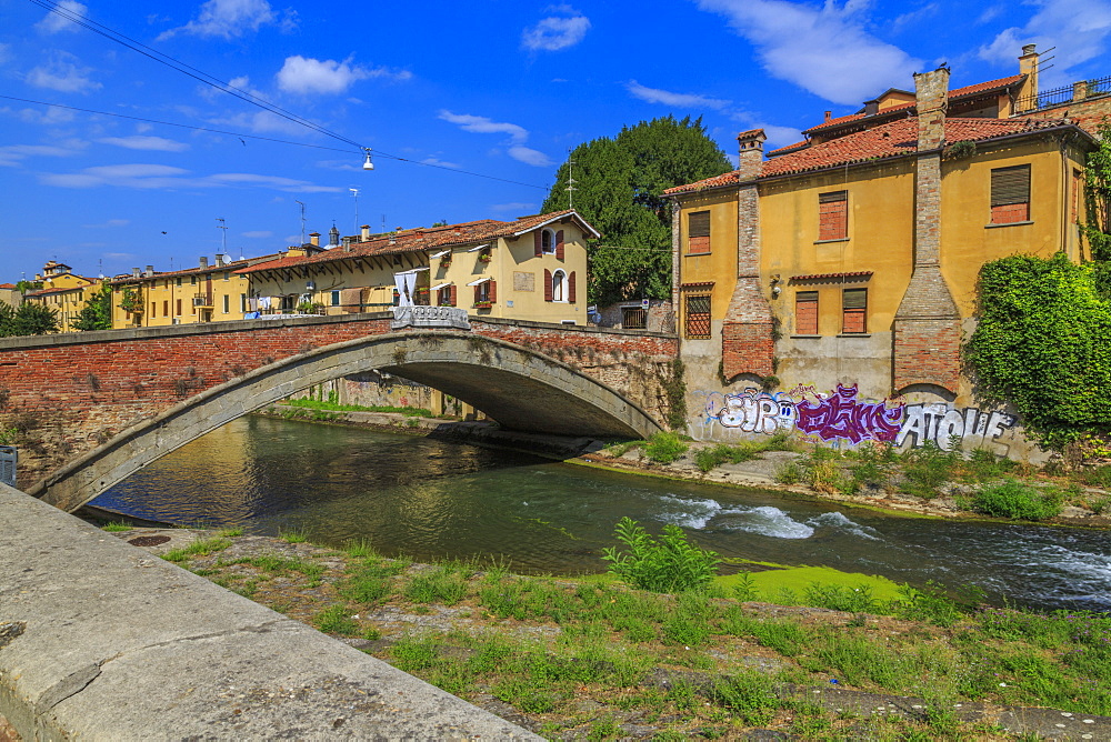 View of pastel coloured properties aligning the river and Ponte San Giovanni delle Navi, Padua, Veneto, Italy, Europe