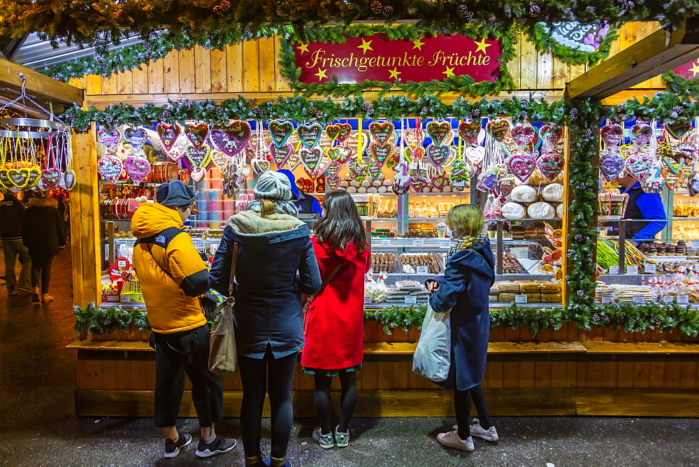 People shopping at Christmas market at night in Rathausplaza, Vienna, Austria, Europe