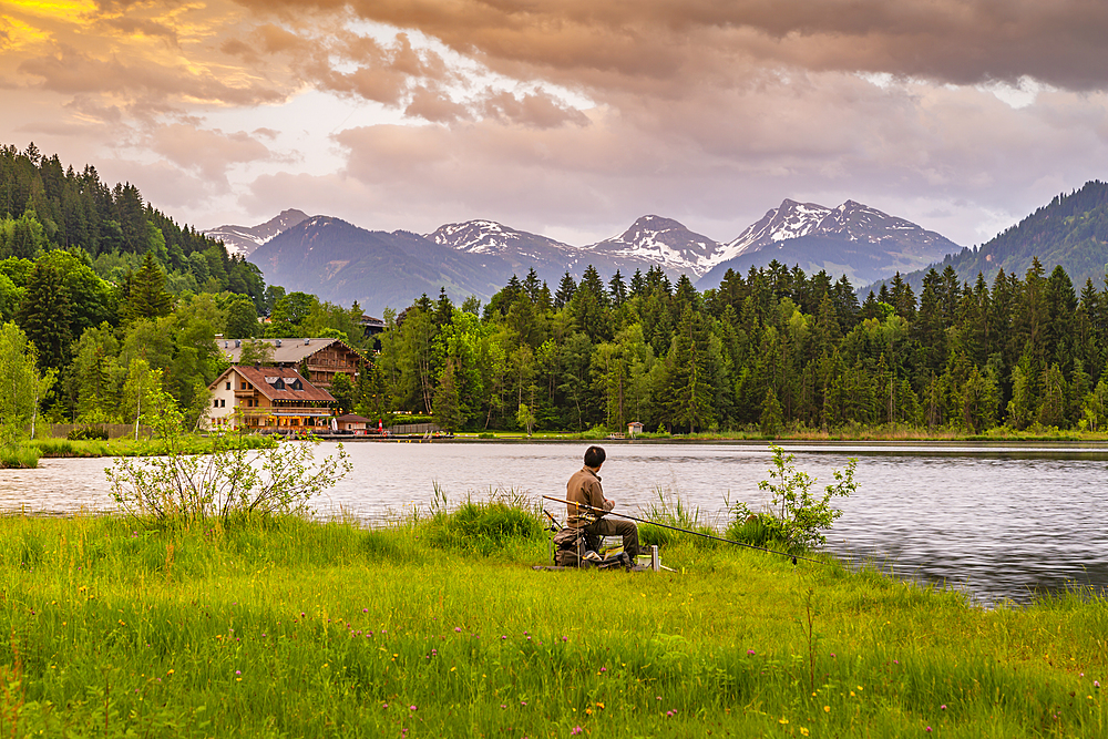 Fisherman and mountainous backdrop at Schwarzsee near Kitzbuhel, Tyrol, Austria, Europe