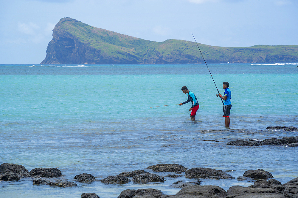 View of beach and men fishing for local restaurant on sunny day in Cap Malheureux, Mauritius, Indian Ocean, Africa