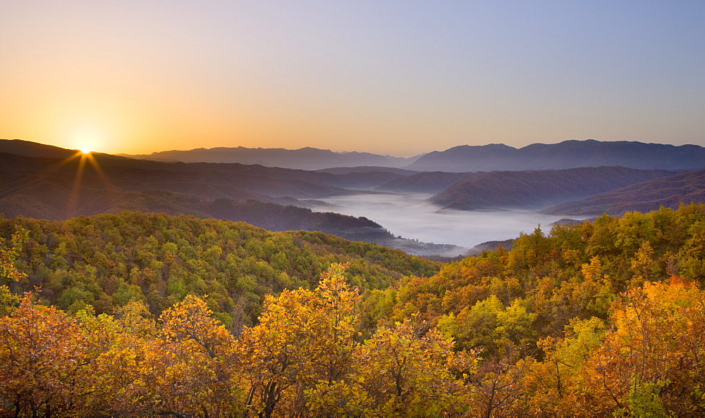 Autumn sunrise in Zagoria with the village of Kipi and a mist filled valley below, Epirus, Greece, Europe