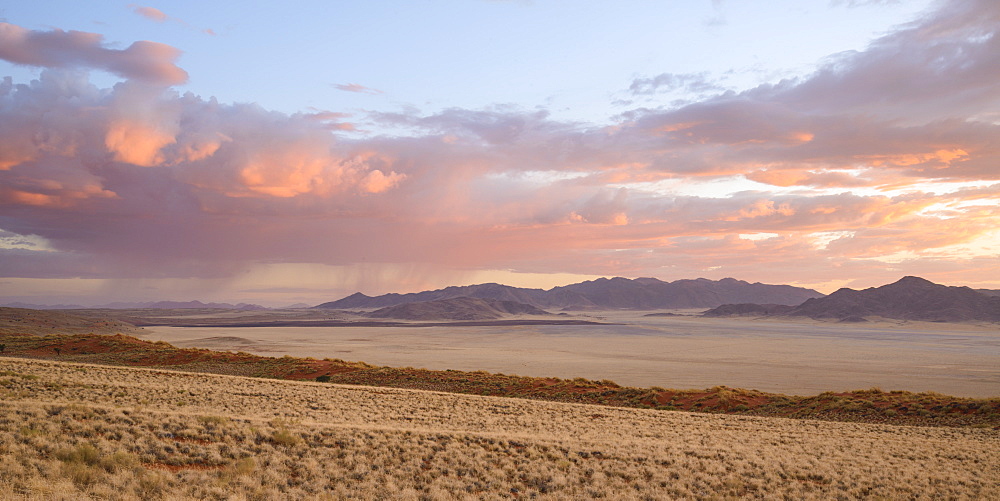 Some much needed rain falls in the distance at dusk in NamibRand Nature Reserve, Namib Desert,  Namibia, Africa