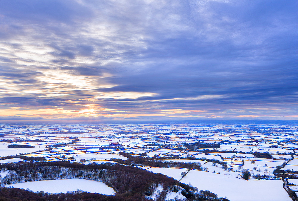 Sinking sun and stormy clouds over a snow covered Gormire Lake from Sutton Bank on the edge of the North Yorkshire Moors, Yorkshire, England, United Kingdom, Europe