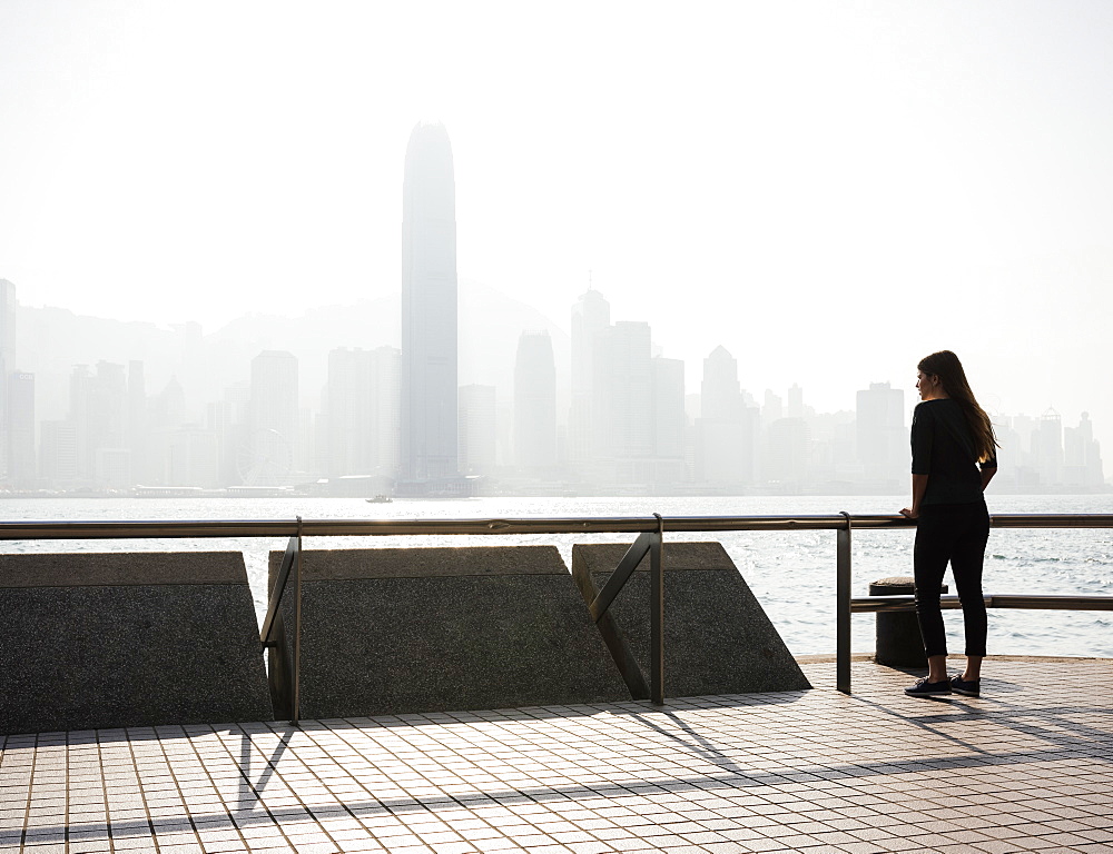 Young woman standing on Tsim Sha Tsui Waterfront, Kowloon, Hong Kong, China, Asia