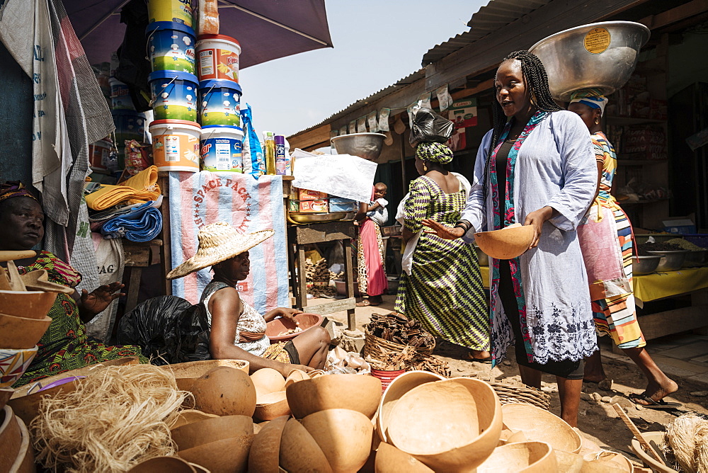 Woman choosing wooden bowl at market stall in Accra, Ghana, Africa