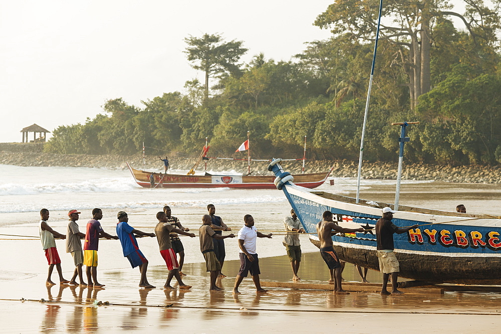 Men pulling boat out to sea, Busua, Ghana, Africa