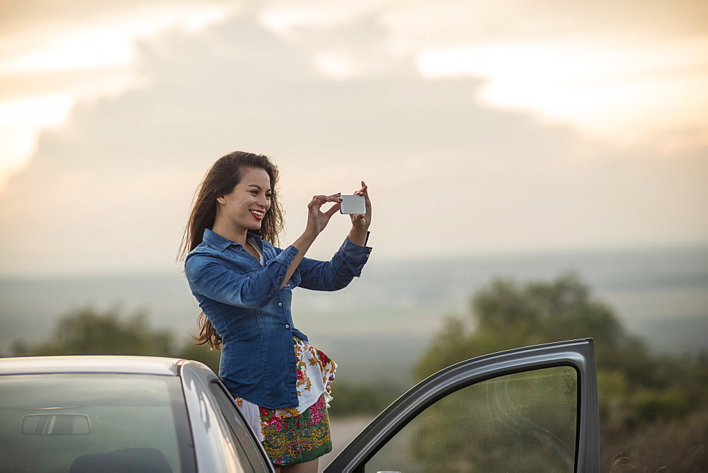 Young woman taking picture with her phone, Mineral de Pozos, Guanajuato, Mexico, North America