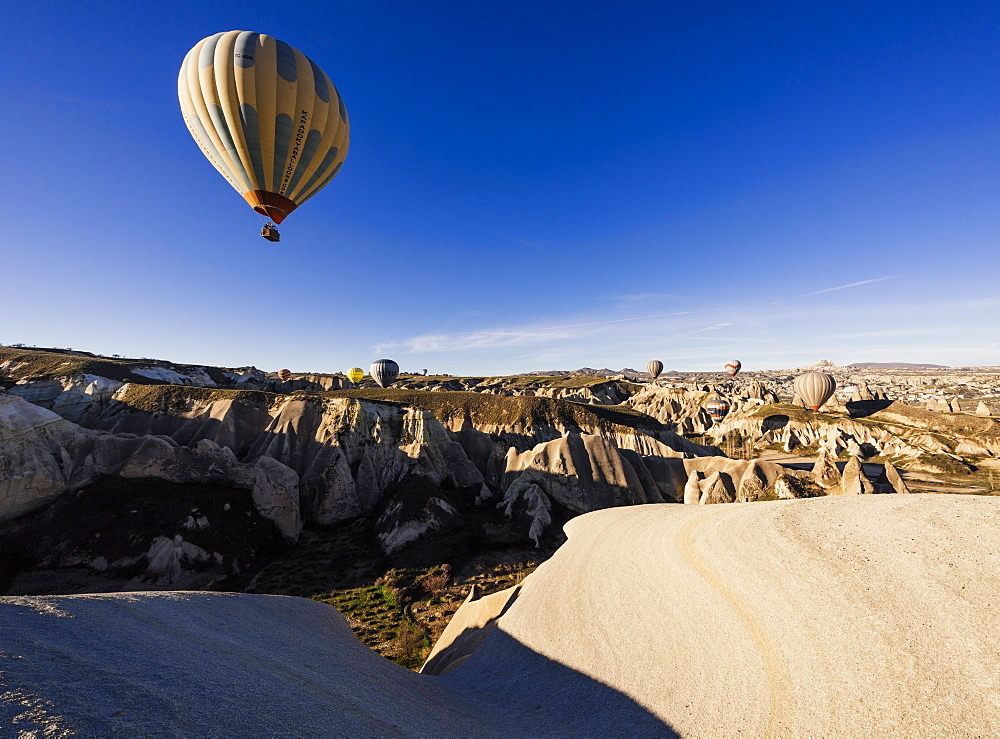 Hot air balloons flying among rock formations at sunrise in the Red Valley, Goreme National Park, UNESCO World Heritage Site, Cappadocia, Anatolia, Turkey, Asia Minor, Eurasia