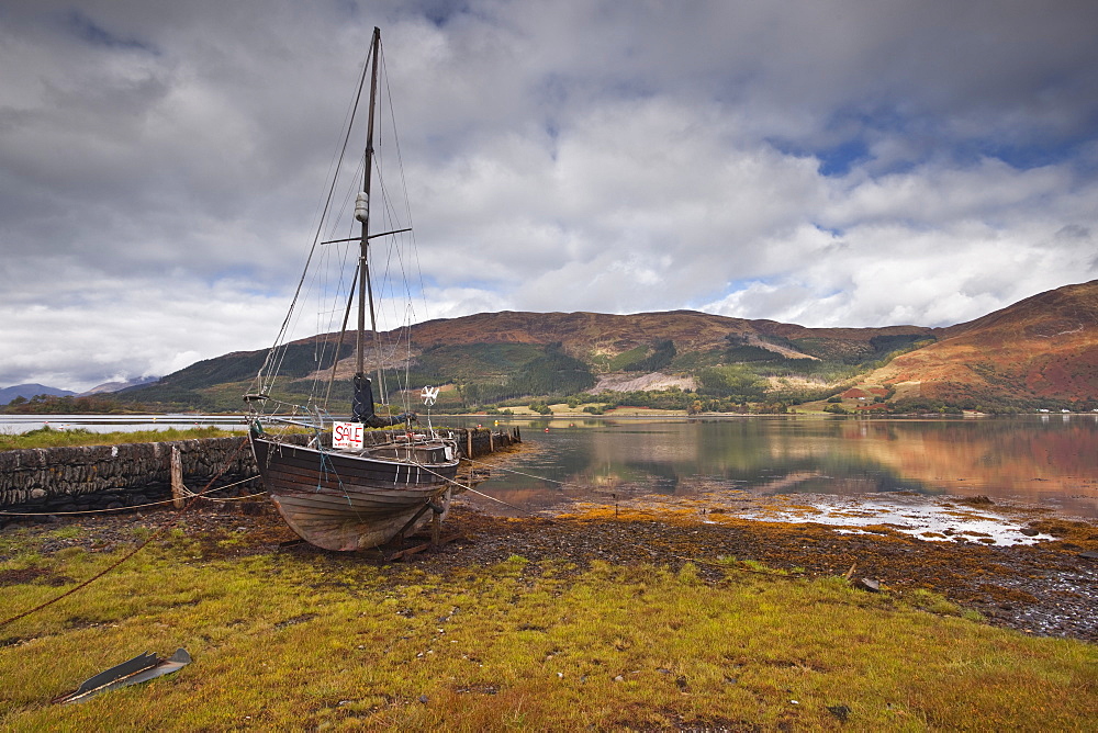 An old boat sits on the shore of Loch Leven in Glencoe, Highlands, Scotland, United Kingdom, Europe