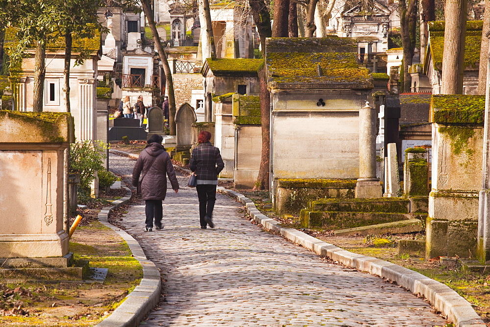 People walking past the gravestones of Pere Lachaise cemetery, Paris, France, Europe