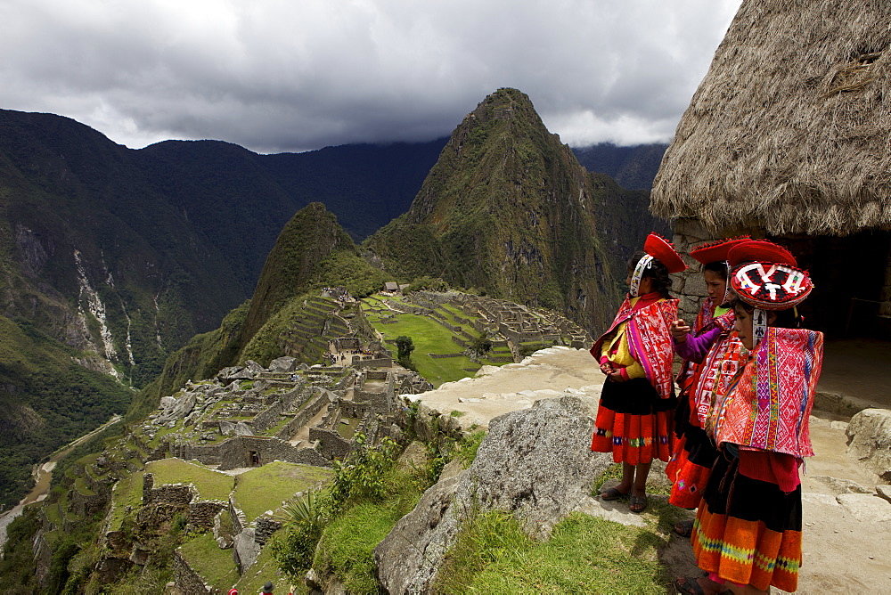 Traditionally dressed children looking over the ruins of the Inca city of Machu Picchu, UNESCO World Heritage Site, Vilcabamba Mountains, Peru, South America