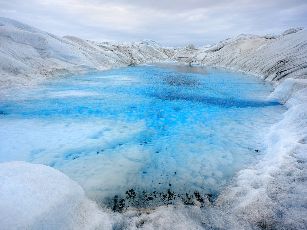 Drainage system with lake on the surface of the ice sheet. The brown sediment on the ice is created by the rapid melting of the ice. Landscape of the Greenland ice sheet near Kangerlussuaq. America, North America, Greenland, danish territory