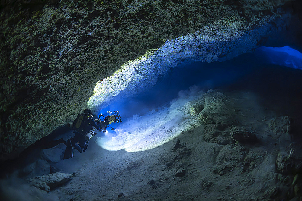 Speleologist diver taking photographs in a karstic cave at Passe Bateau Sud at a depth of 60 metres, Mayotte