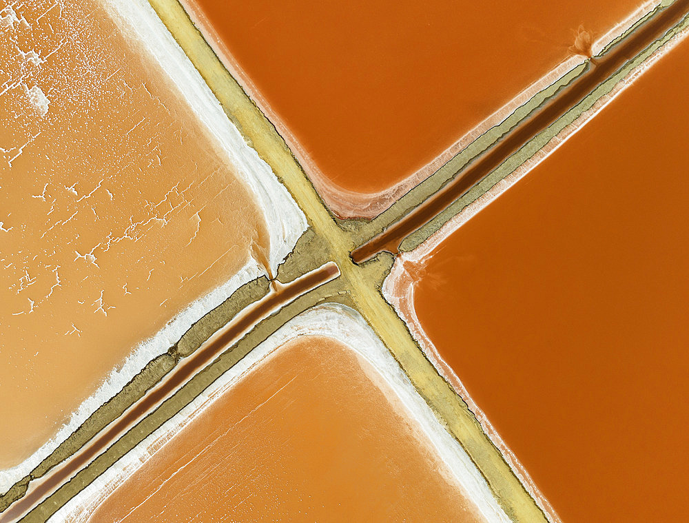 Saline ponds at the Bonanza salt works near Sanlúcar de Barrameda. The reddish colour depends on the level of salinity and is directly caused by the algae Dunaliella salina and brine shrimp. Aerial view. Drone shot. Cádiz province, Andalusia, Spain.