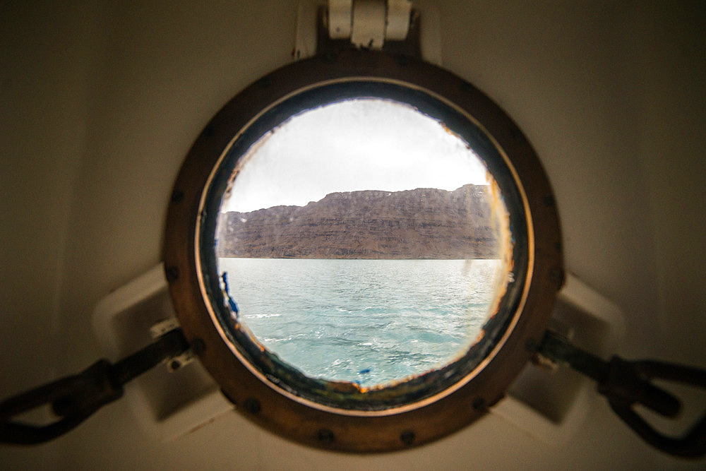 The view from a porthole. It's a magical moment. It's early in the morning and we're finally discovering a piece of the island on which we'll spend 13 months. Table Bay, Kerguelen Archipelago