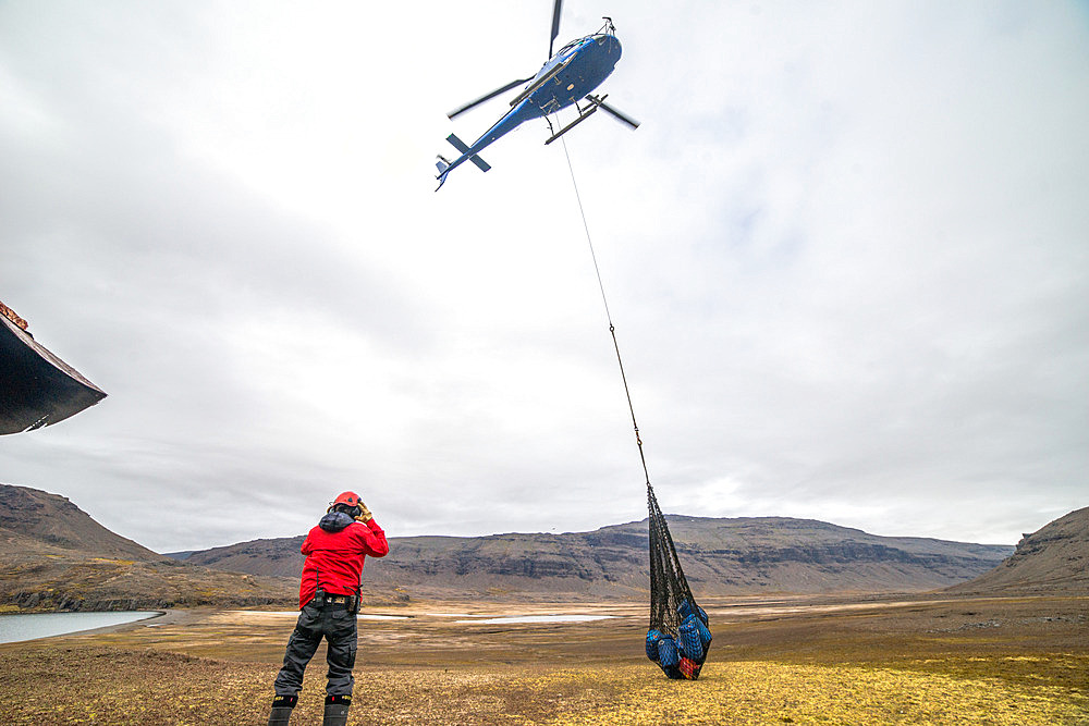Supplying the Val Studer hut by helicopter. The helicopter drops a net, or "sling", containing several drums filled with equipment and food. Kerguelen Archipelago