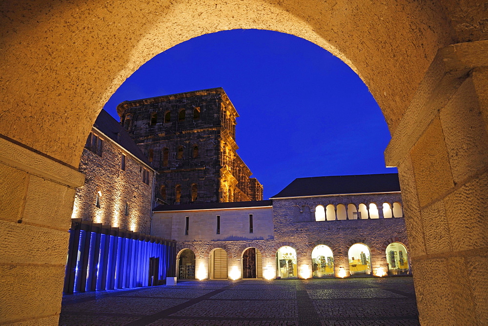 Porta nigra with archway and fountain court illuminated at night