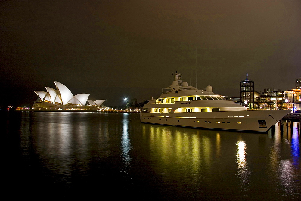 a night lit scene with a large yacht looking across Sydney Harbour to the iconic Opera House Sydney New South Wales