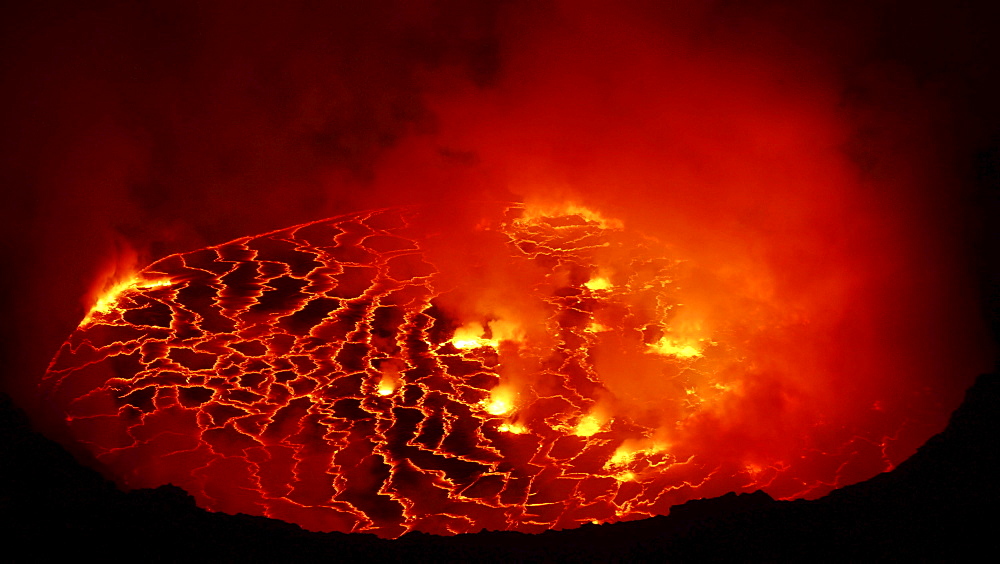 volcano Nyiragongo crater with lava fountains in the lava lake rising smoke nature natural phenomenon night view Kongo Afrika