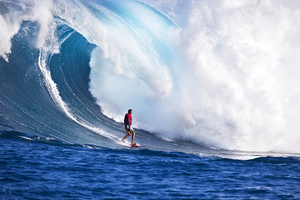 A tow, in surfer drops to the curl of Hawaii's big surf at Peahi Jaws off Maui