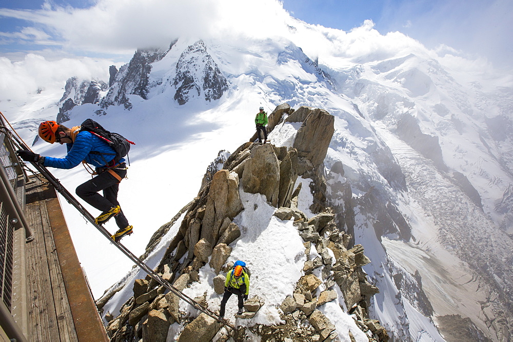 Mont Blanc from the Aiguille Du Midi above Chamonix, France, with climbers on the Cosmiques Arete, climbing the ladder to access the cable car station.