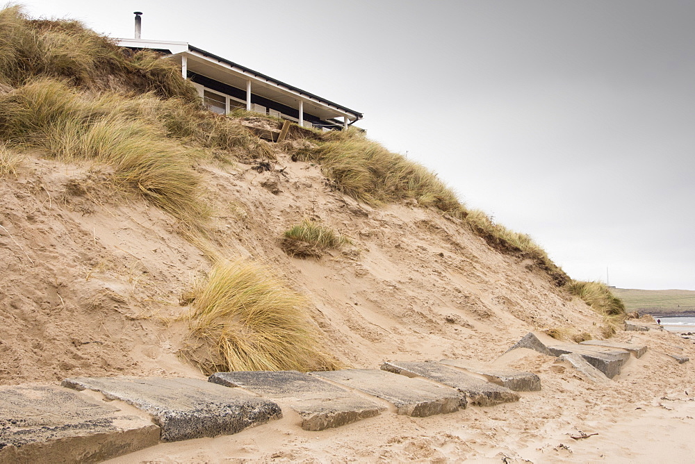 A holiday chalet in the sand dunes at low Newton by the Sea on Northumberland's coast stands precarioulsy close to the edge following a severe storm surge in December 2013 that caused considerable erosion to the sand dunes.