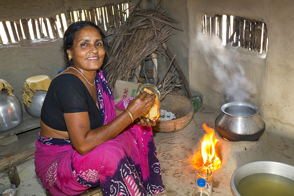 A villager woman in a remote subsistence farming village on an island in the Sunderbans, the Ganges Delta in Eastern India that is very vulnerable to sea level rise. She is cooking on a traditional clay oven, fuelled by biofuel (rice stalks), low carbon cooking.