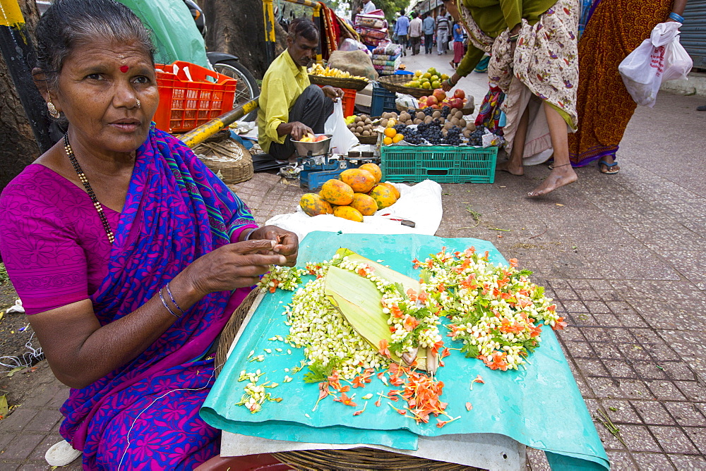 A woman making floral hair decorations at a street market in Mysore, India.