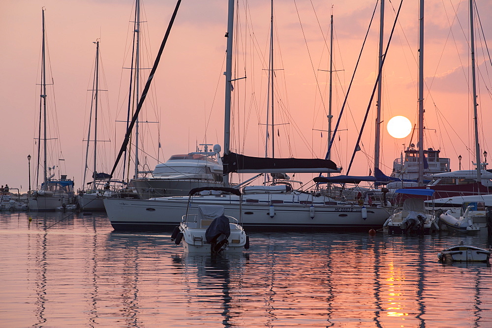 Sailing boats in the harbour at Sivota in Greece at sunset.