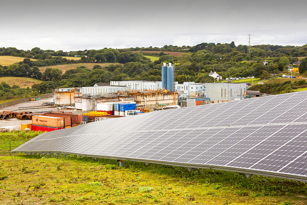 A solar park at Wheal Jane an old abandoned Cornish tin mine near Redruth, UK, that is rediscovering itself as a renewable energy hub, with the old mine buildings in the background.