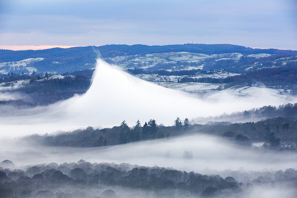 Looking down into the Langdale Valley above valley mist formed by a temperature inversion on Loughrigg, near Ambleside in the Lake District National Park. Localised warming has caused this very rare weather phenomenon, and lifted the mist up into a volcano shape.