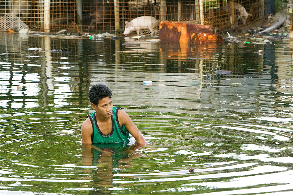 Boy wading in the floodwater caused by sea water incursion due to global warming induced sea level rise that threatens the future of these low lying islands, Funafuti Atoll, Tuvalu, Pacific