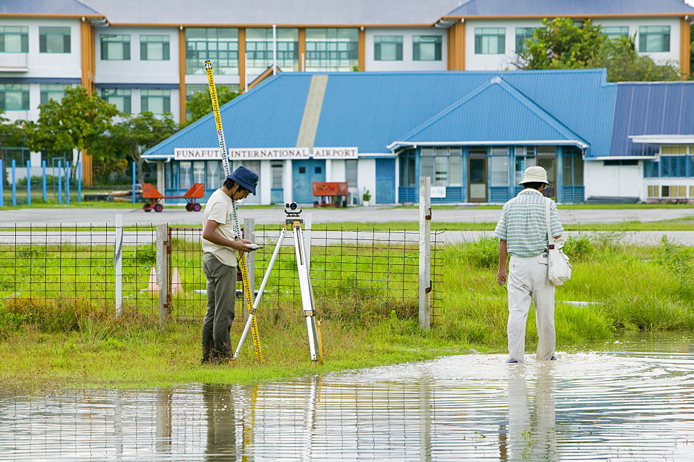 Surveying the floodwater caused by sea water incursion due to global warming induced sea level rise that threatens the future of these low lying islands, Funafuti Atoll, Tuvalu, Pacific