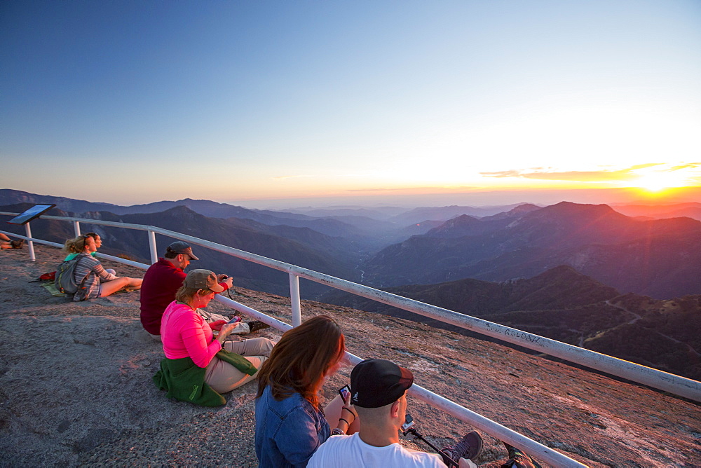 Tourists on the summit of Moro Rock a granite outcrop viewpoint in the Sequoia National Park, Yosemite, USA at sunset.