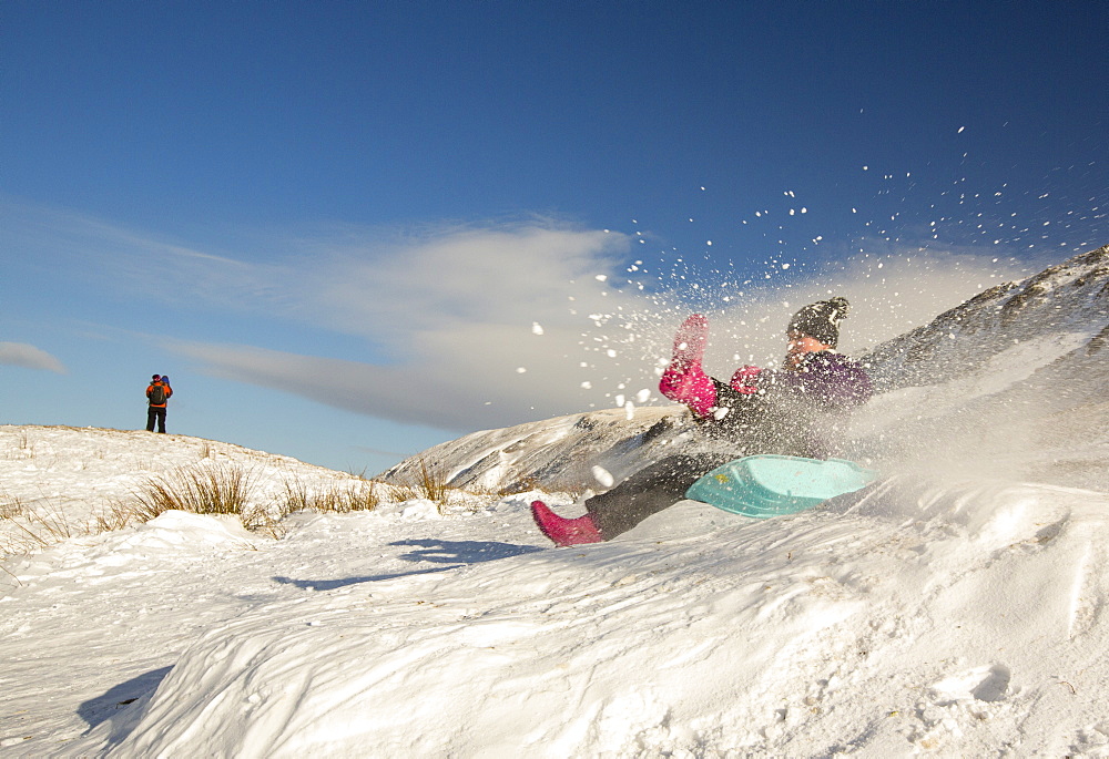 A girl sledging on Kirsktone Pass in the Lake District, UK