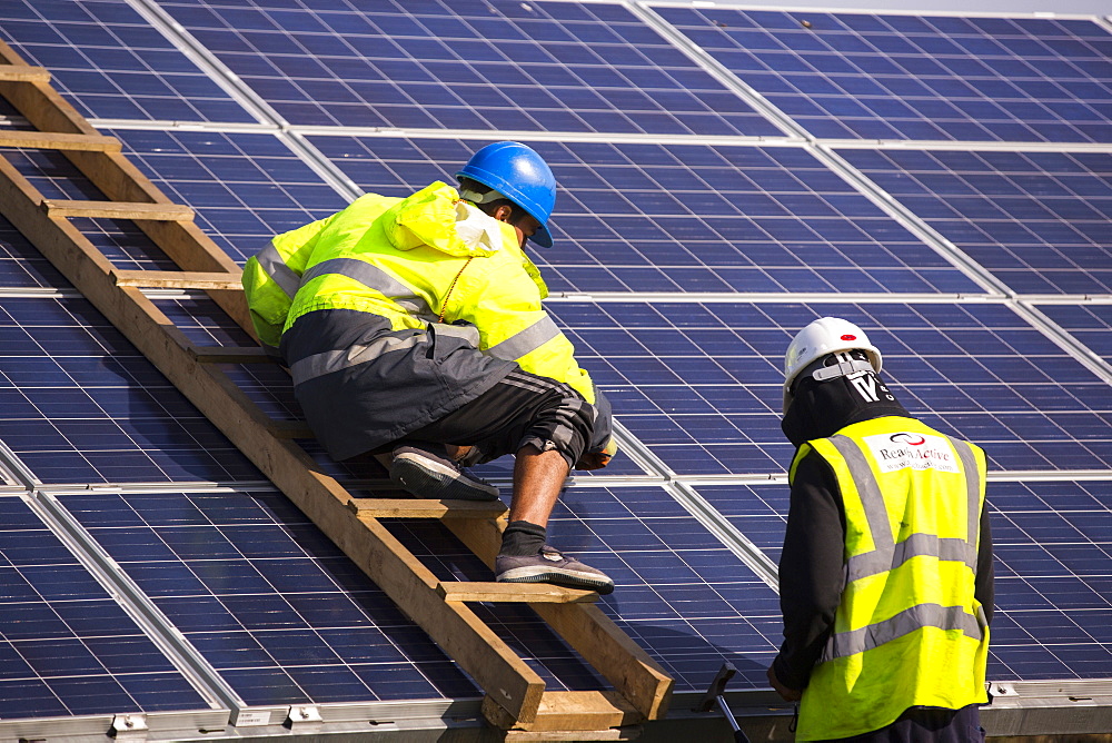 Technicians work on Wymeswold Solar Farm the largest solar farm in the UK at 34 MWp, based on an old disused second world war airfield, Leicestershire, UK. It contains 130,000 panels and covers 150 acres.