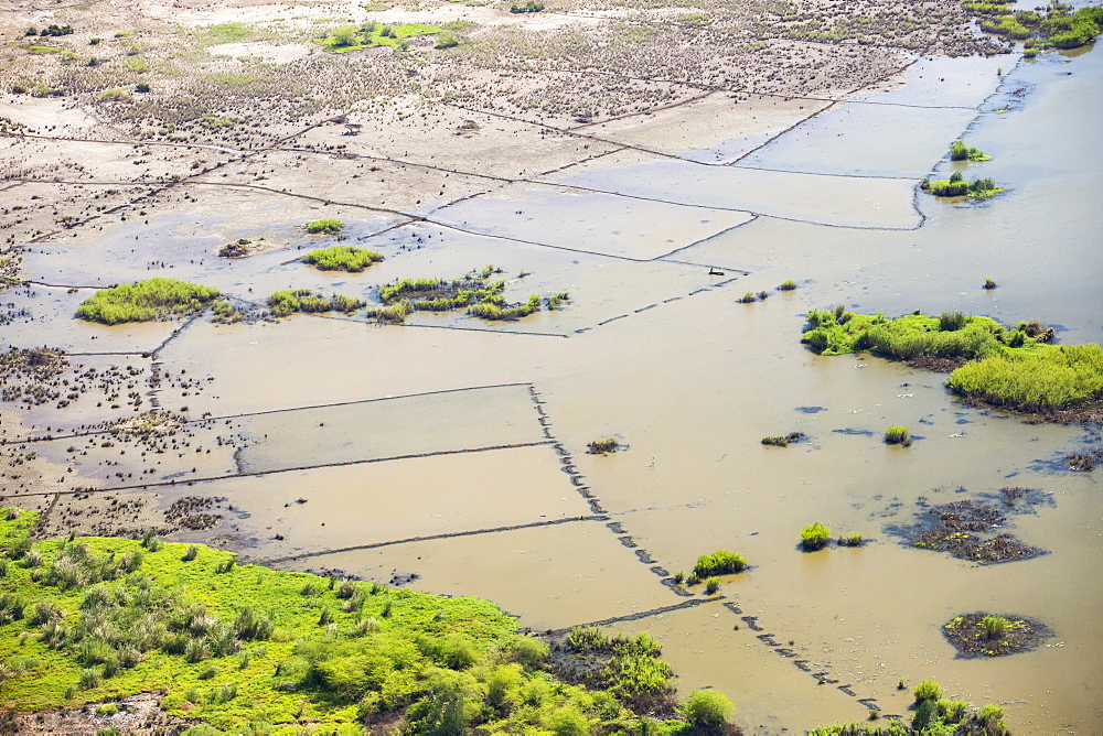 In mid January 2015, a three day period of excessive rain brought unprecedented floods to the small poor African country of Malawi. It displaced nearly quarter of a million people, devastated 64,000 hectares of land, and killed several hundred people. This shot taken from the air on a flight to Makhanga, which two months on, is still cut off by the floods when all rail and road connections were washed away, is looking down on the flood waters still sat on the flood plain, and the devastated farmland.