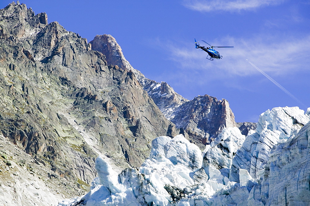 A tourist hericopter traverses melting seracs on the snout of the Argentiere Glacier, like most Alpine glaciers it is retreating rapidly due to global warming, Chamonix, Haute Savoie, France, Europe