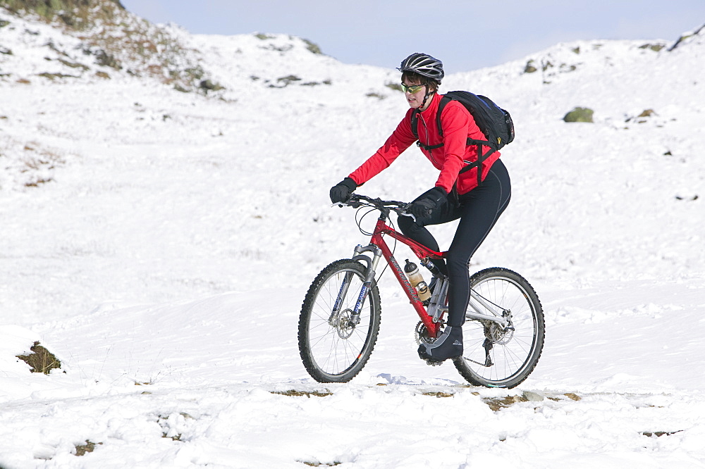 A mountain biker and snowfall, Lake District, Cumbria, England, United Kingdom, Europe