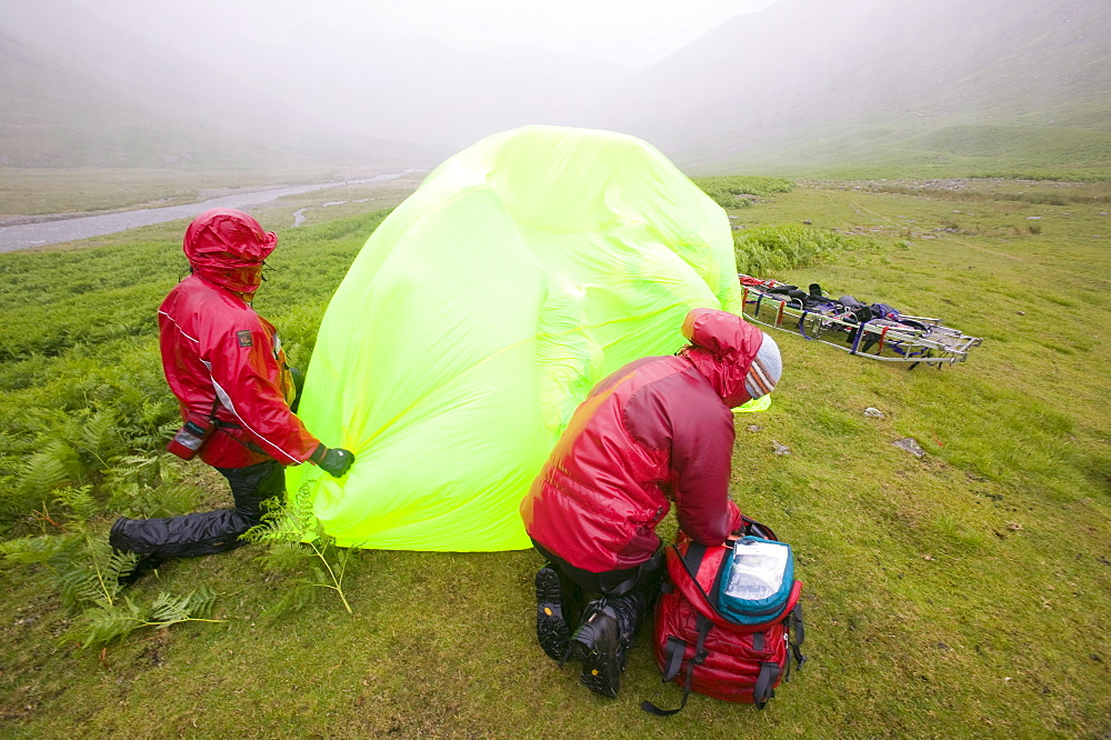 Members of Langdale Ambleside mountain rescue Team treat a collapsed walker suffering from hypothermia protected from the foul weather by a group shelter, Lake District, Cumbria, England, United Kingdom, Europe