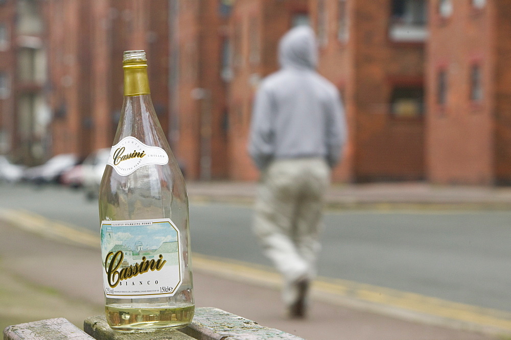 A cheap bottle of wine abandoned by a street drinker amongst tenement flats on Barrow Island, Cumbria, England, United Kingdom, Europe