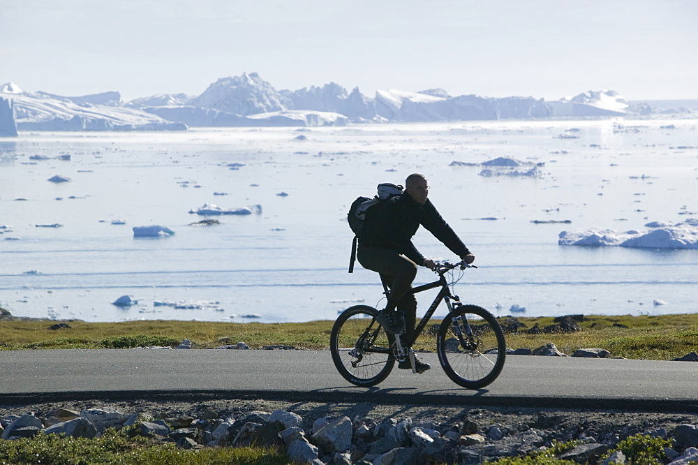 Man cycling near the Jacobshavn glacier (Sermeq Kujalleq), Greenland, Polar Regions