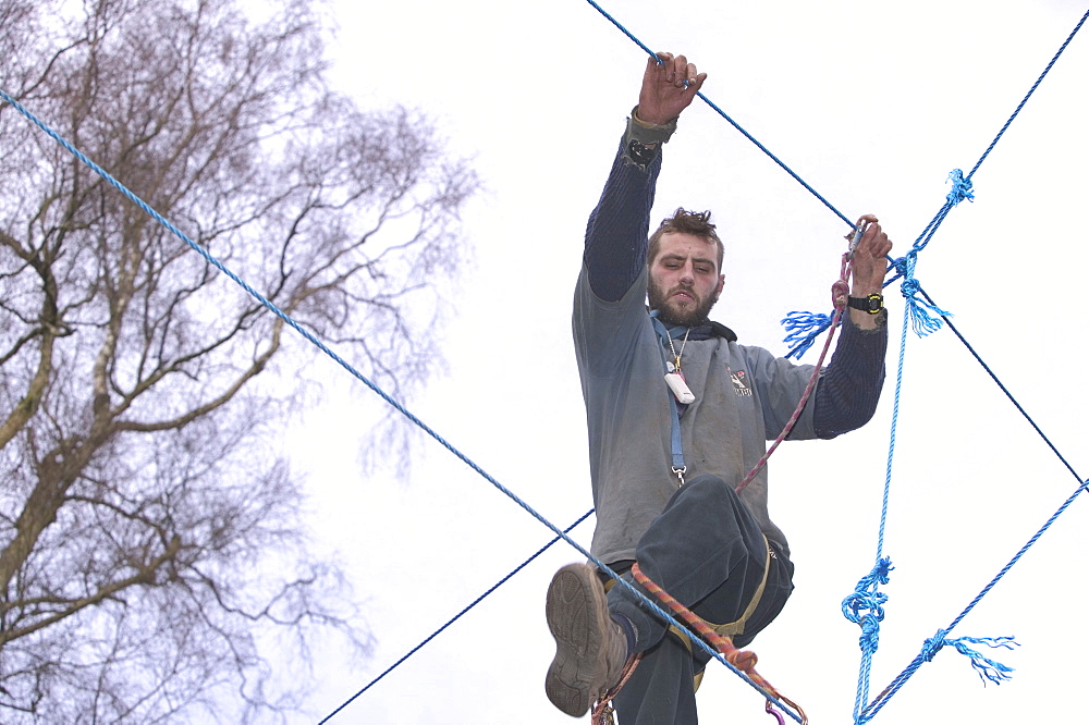 Environmental protestor at the Nine Ladies stone circle camp takes to ropes to avoid bailiffs, Derbyshire, England, United Kingdom, Europe