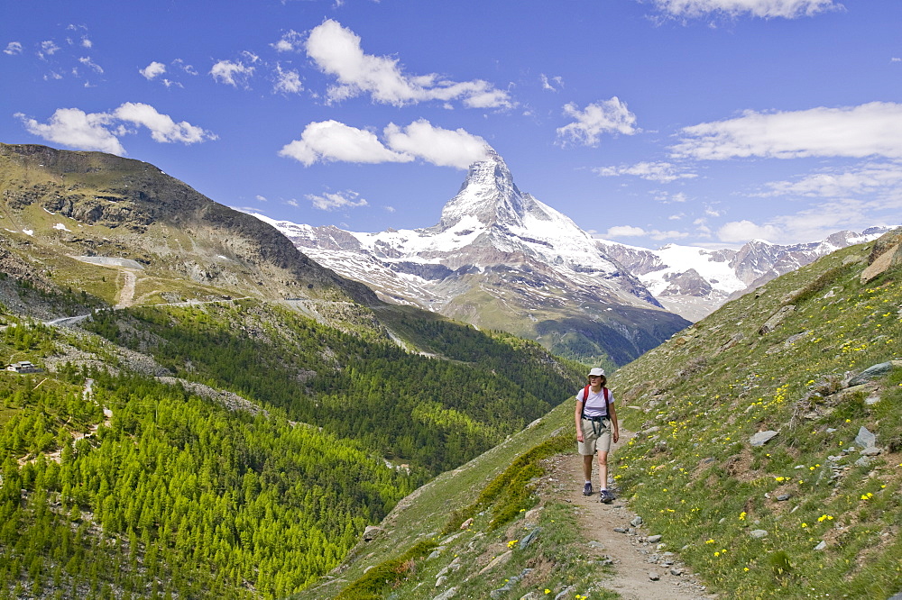 A woman walking in front of the Matterhorn above Zermatt, Switzerland, Europe