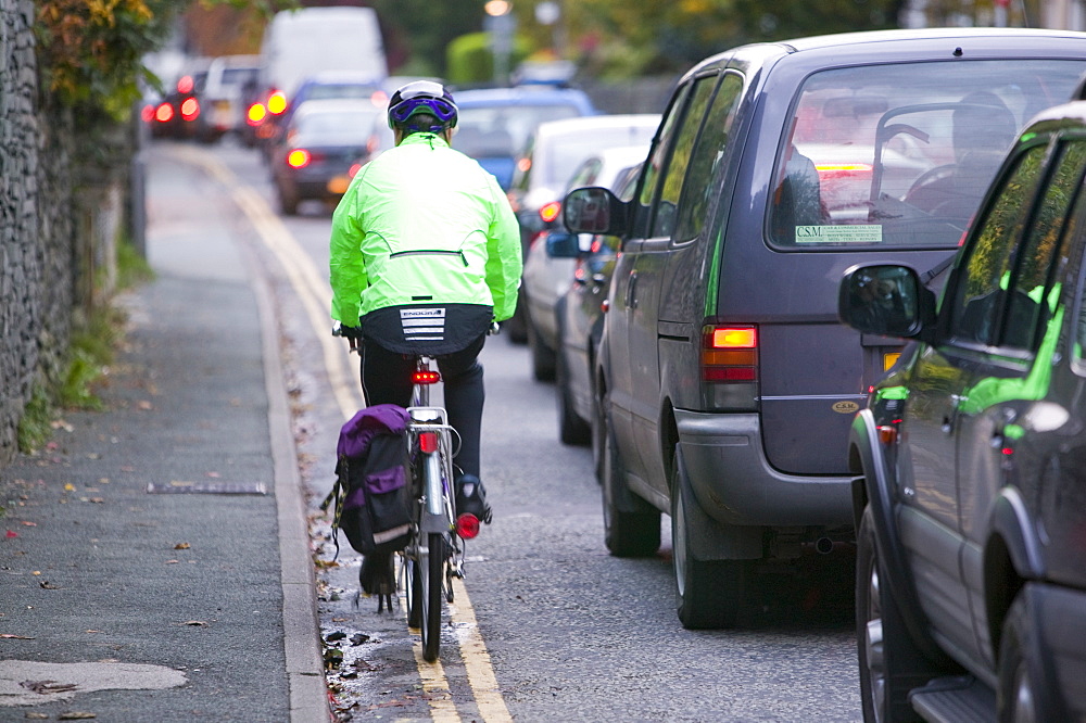 Cycling through a traffic jam in Ambleside, Cumbria, England, United Kingdom, Europe