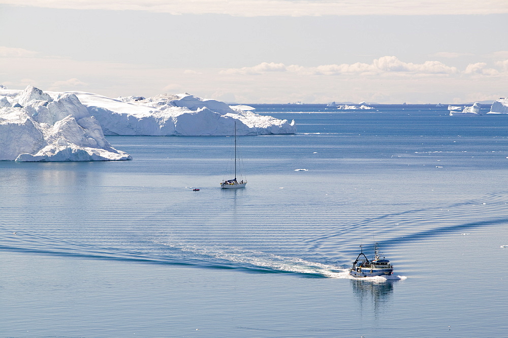 An Inuit fishing boat sails through icebergs from the Jacobshavn Glacier (Sermeq Kujalleq), Greenland, Polar Regions