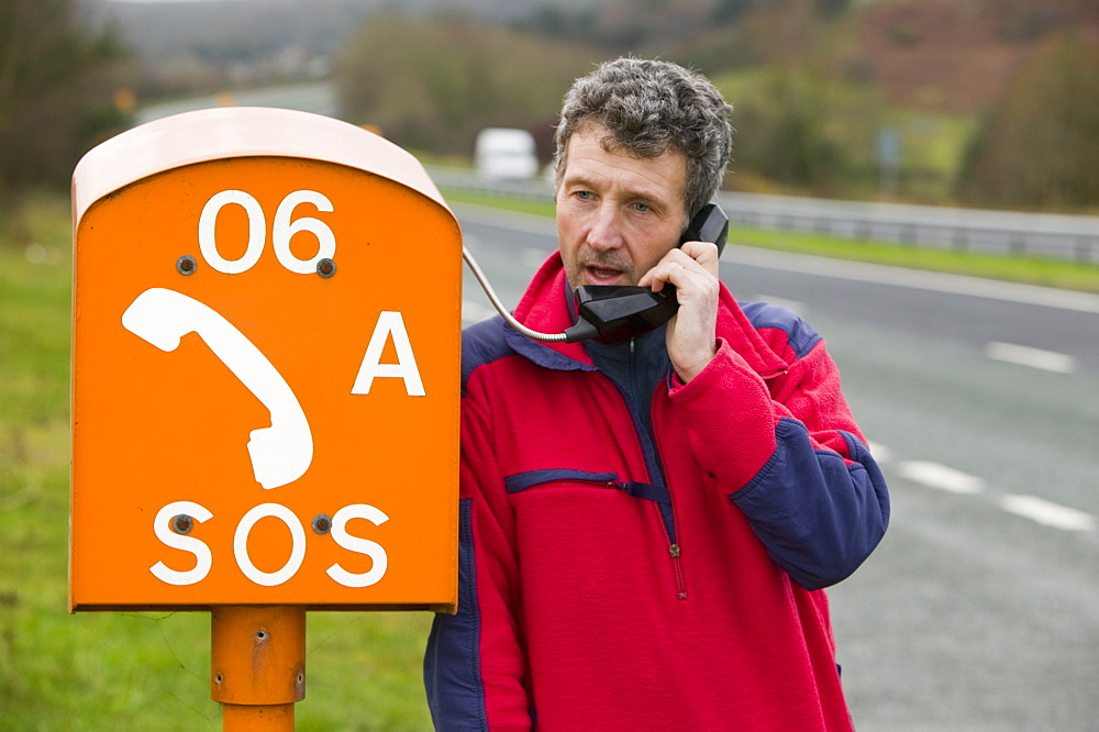 A motorist using an SOS phone by the roadside