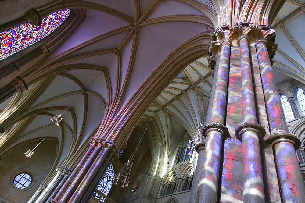 Light from stained glass windows on pillars in Lincoln Cathedral, Lincoln, Lincolnshire, England, United Kingdom, Europe