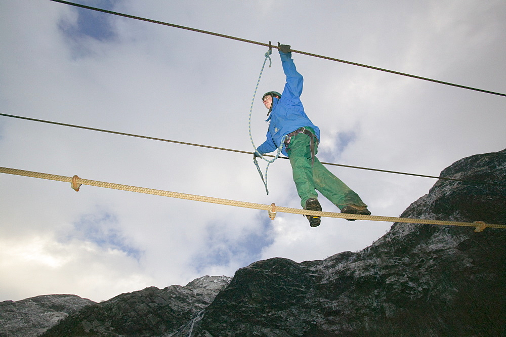 A climber crossing the steal rope bridge in Glen Nevis, Scotland, United Kingdom, Europe