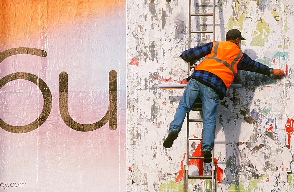 A man working on a bill board in Loughborough, Leicestershire, England, United Kingdom, Europe